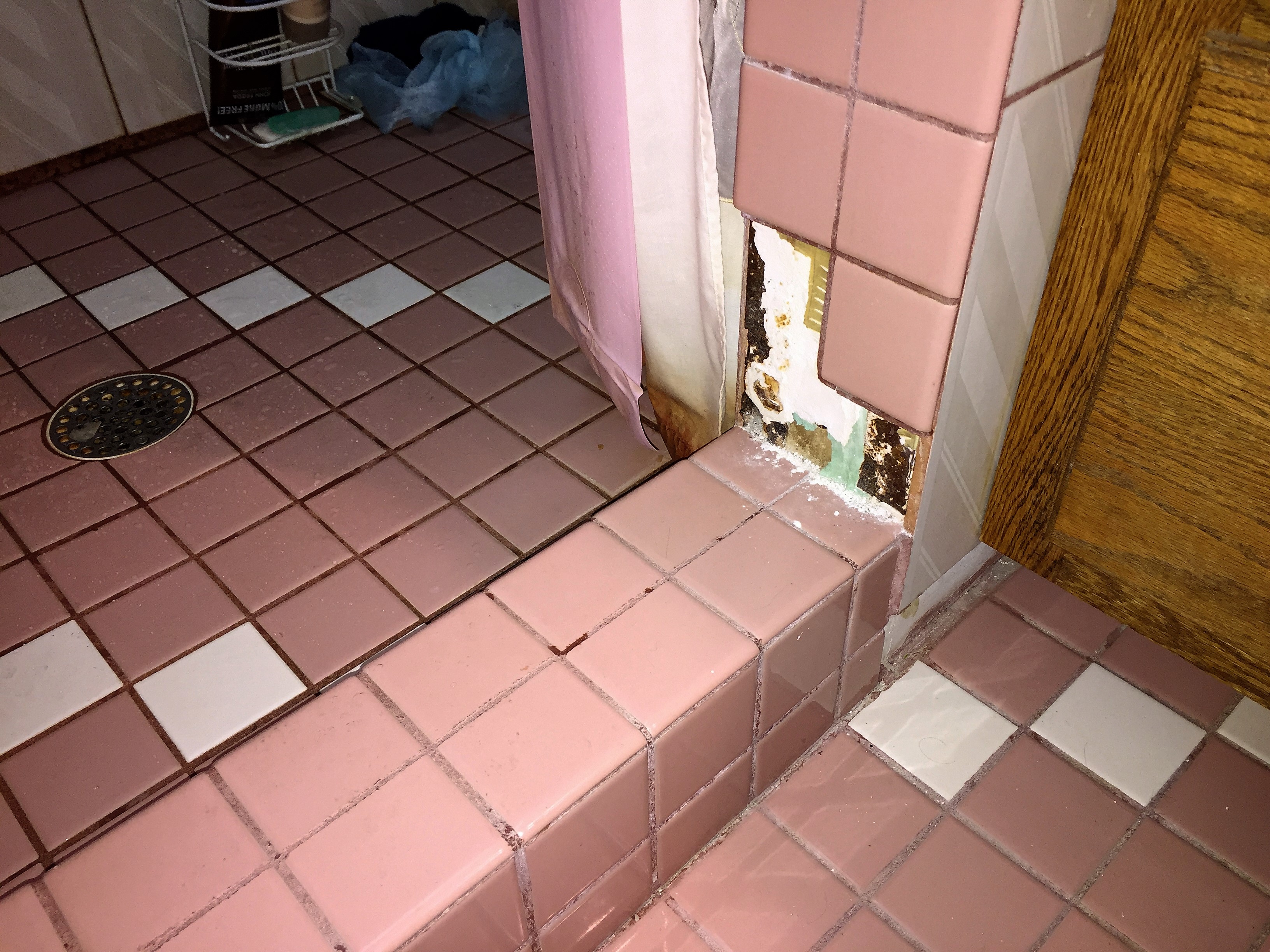 Ugly old pink floor tiles with damage before bathroom remodel